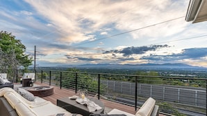 A deck with outdoor furniture, a fire pit, and a scenic view of the landscape.