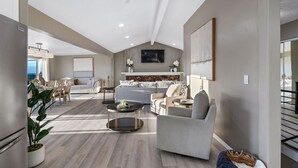 A spacious living room with a high ceiling, a dining area, and a view of the ocean.