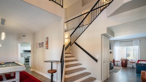 Un intérieur moderne, comprenant un escalier, une table de billard et un coin cuisine.