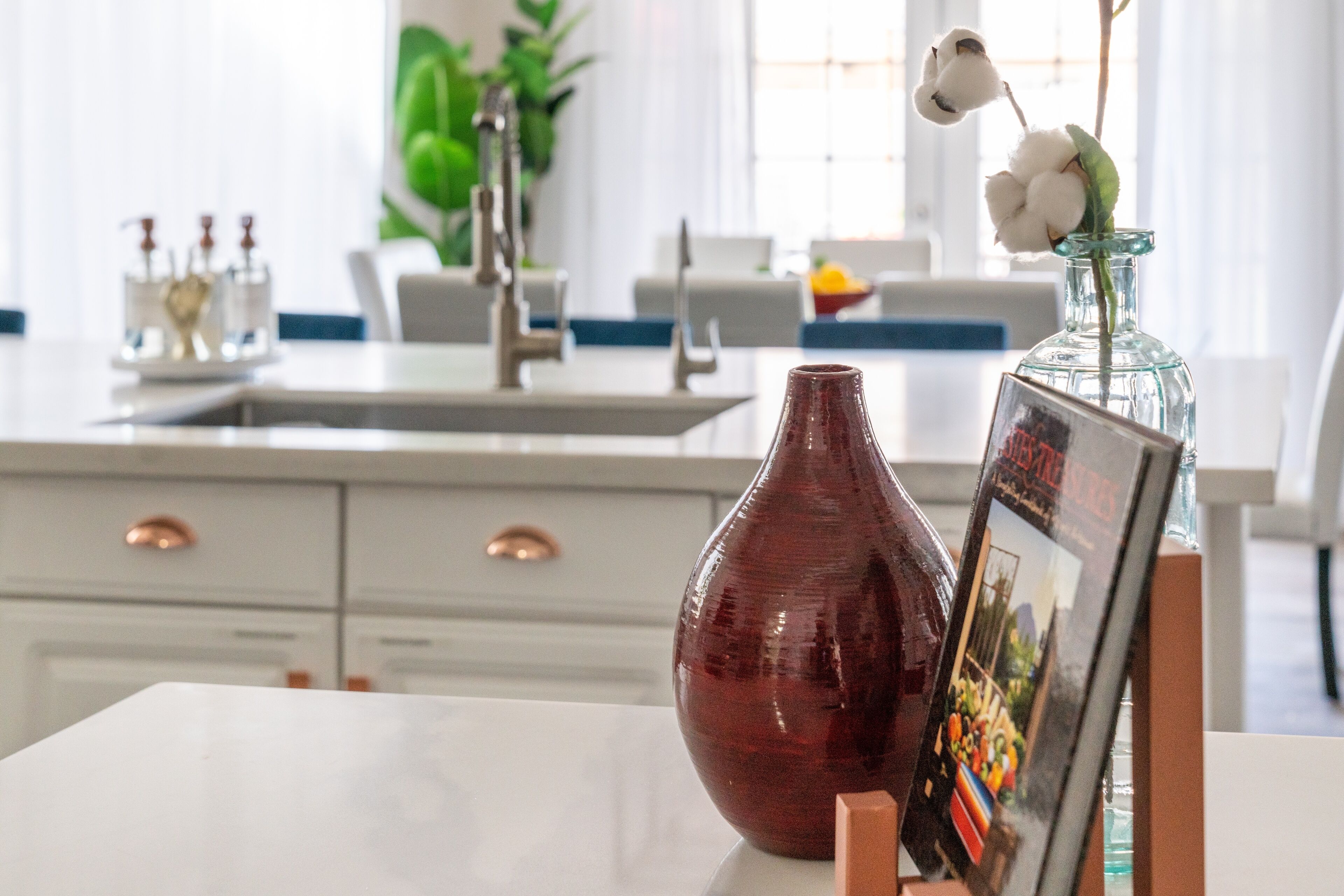A kitchen with white cabinets, a marble countertop, and a vase with a picture frame on it.