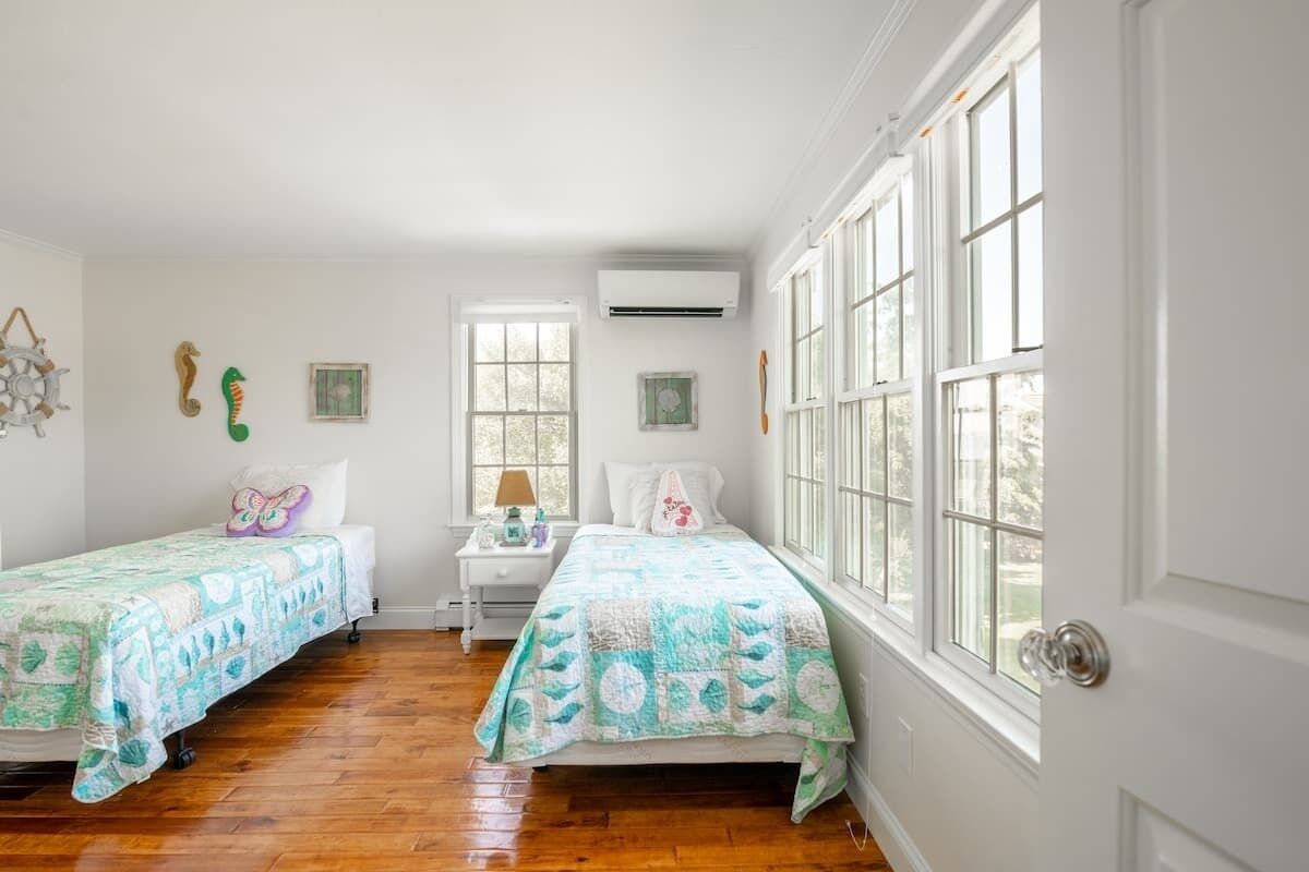 A room with two beds, a nightstand, and a window with a view.