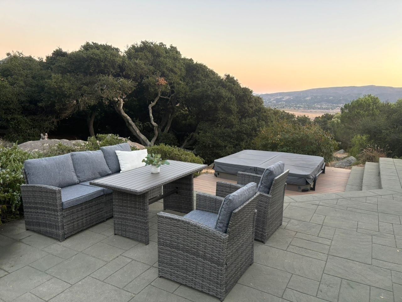 An outdoor patio with wicker furniture, including a sofa, chairs, and a table.
