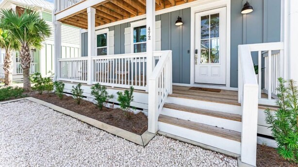 A two-story house with a porch, a wooden deck, and a gravel driveway. - Port St Joe Beach House Pool 5BR Sleeps 12 by RedAwning (Port St. Joe)