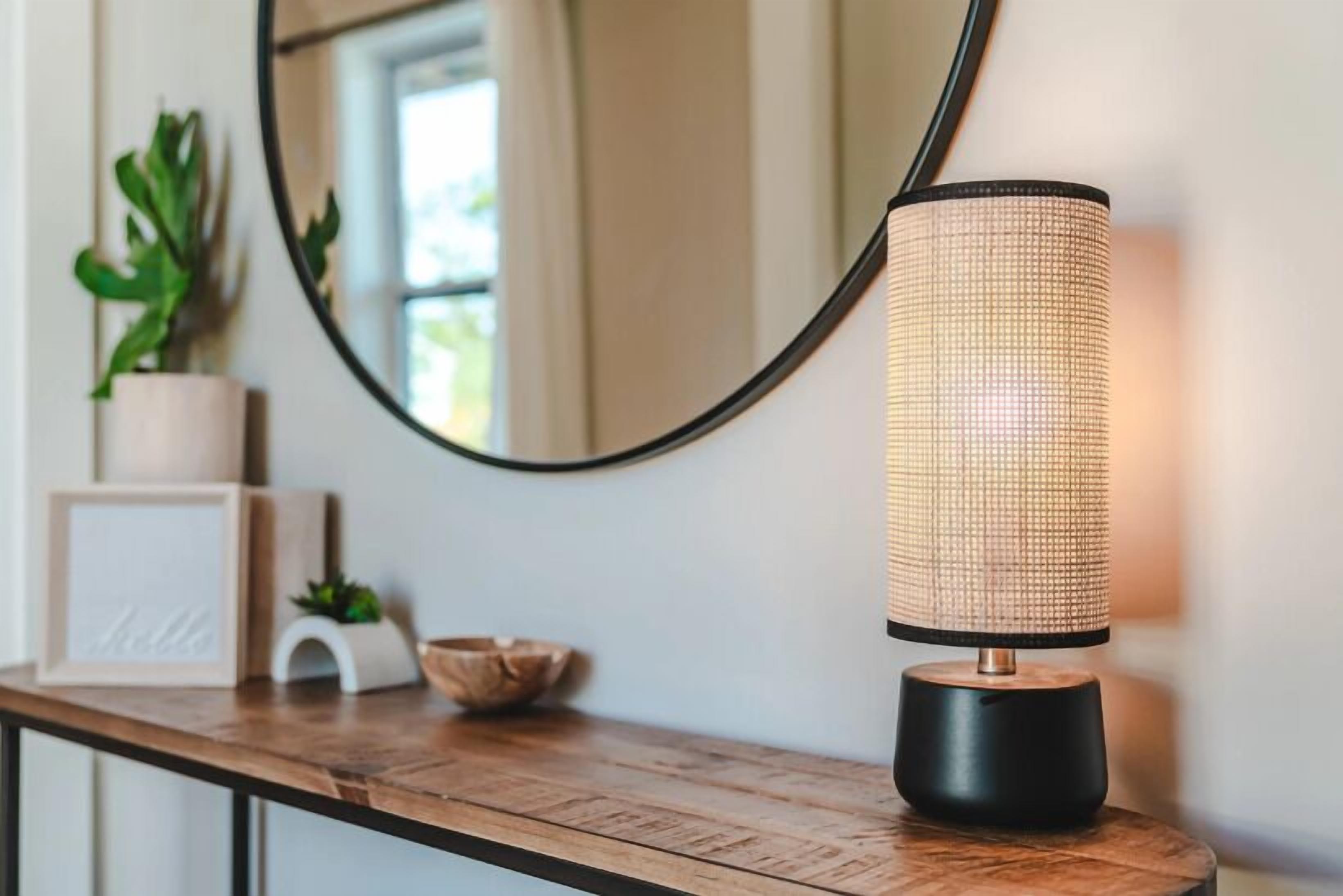 A modern lamp with a textured shade on a wooden table.