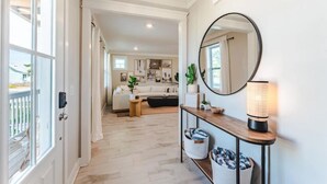 A hallway leading to a living area with a sofa, a round mirror, and a table with a lamp. - Port St Joe Beach House Pool 5BR Sleeps 12 by RedAwning (Port St. Joe)