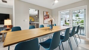 Un comedor moderno con una larga mesa de madera, sillas azules y un ventilador de techo.