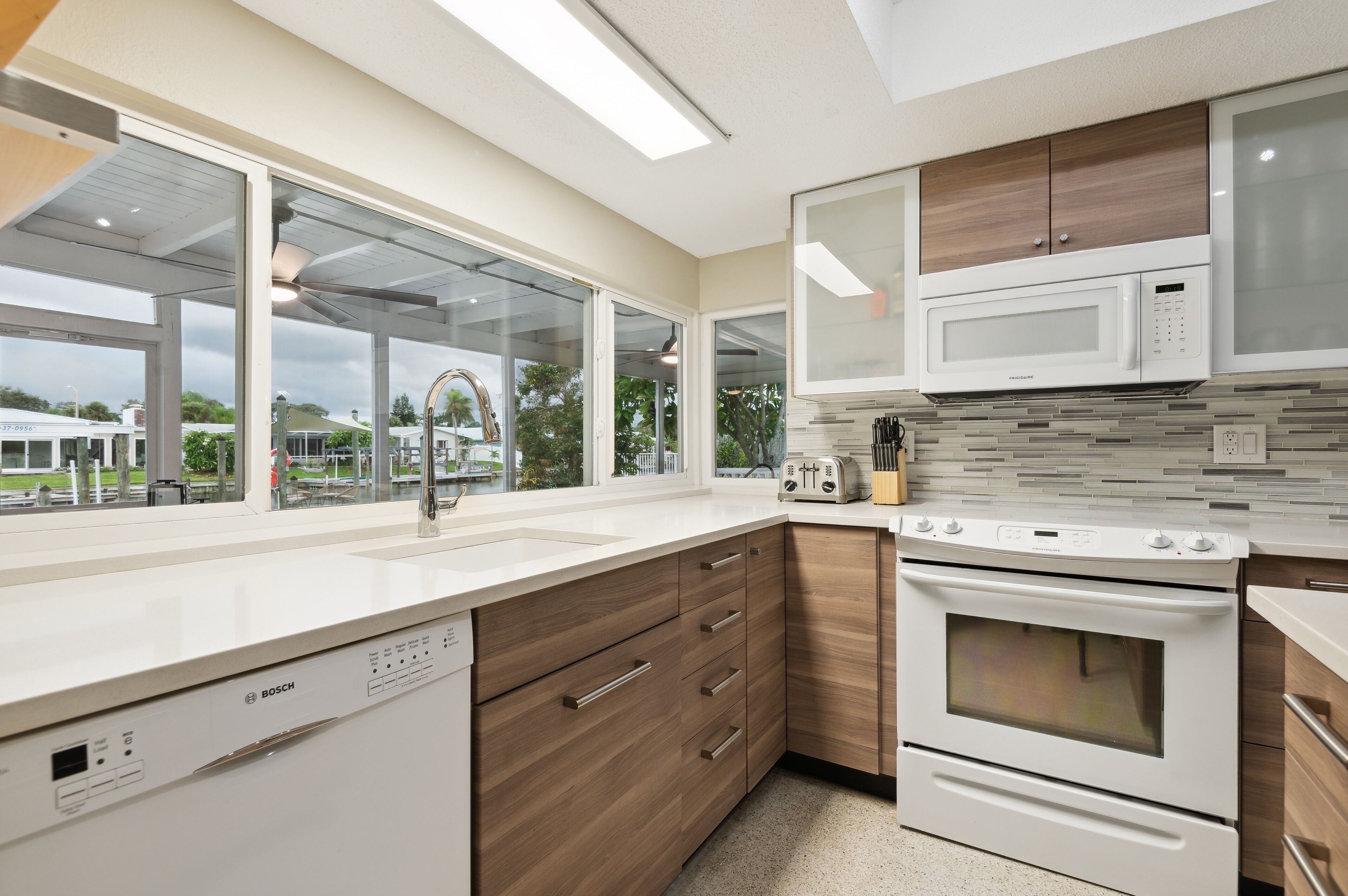 A modern kitchen with a dishwasher, microwave, oven, and wooden cabinets.