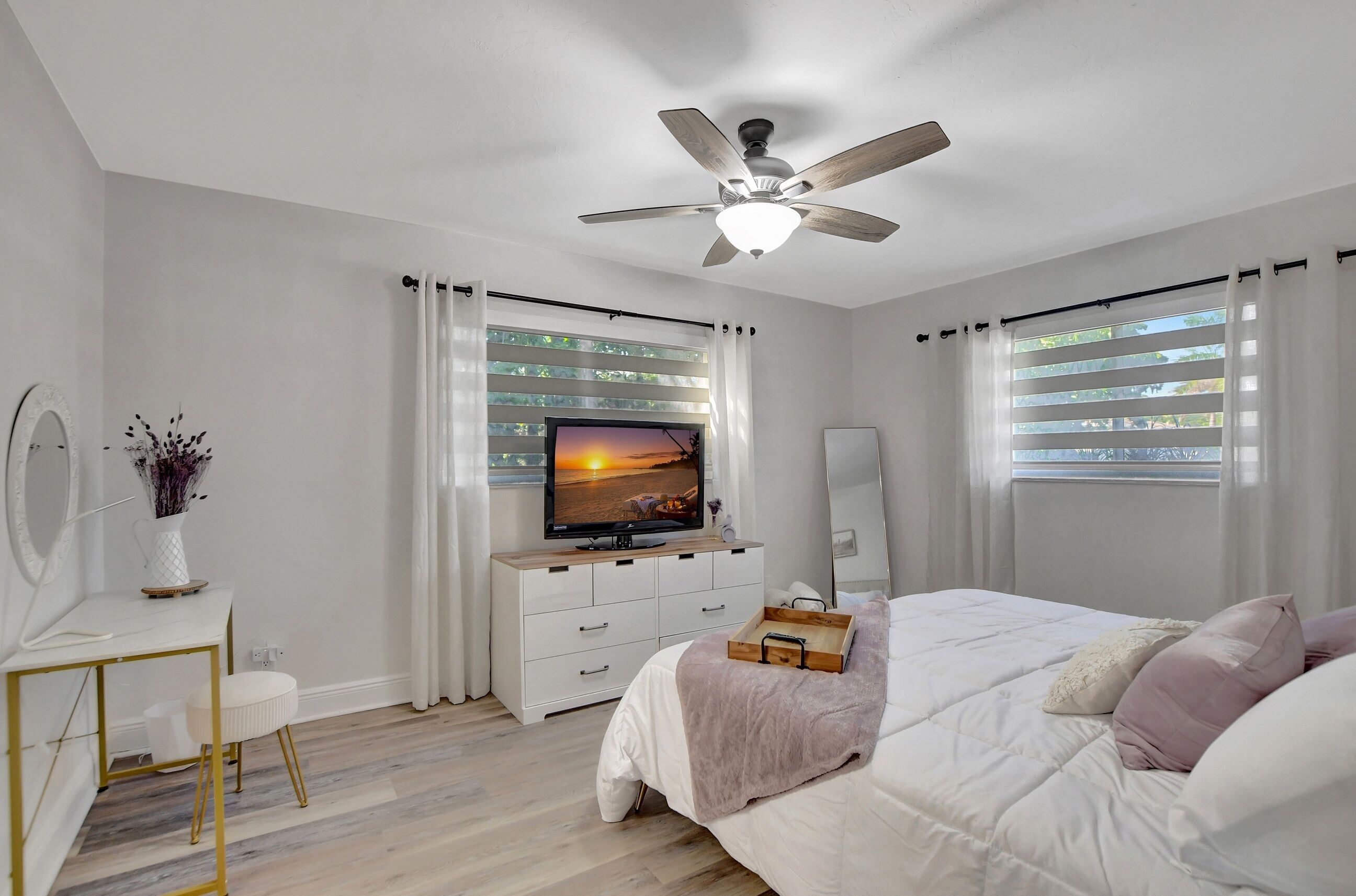 Ein Schlafzimmer mit Bett, Fernseher, Schreibtisch und Deckenventilator.