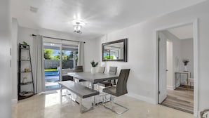 A modern dining area with a table, chairs, and a bench. - Boca Beauty - Stylish Home With Pool 3 Bedroom Home by RedAwning (Boca Raton)