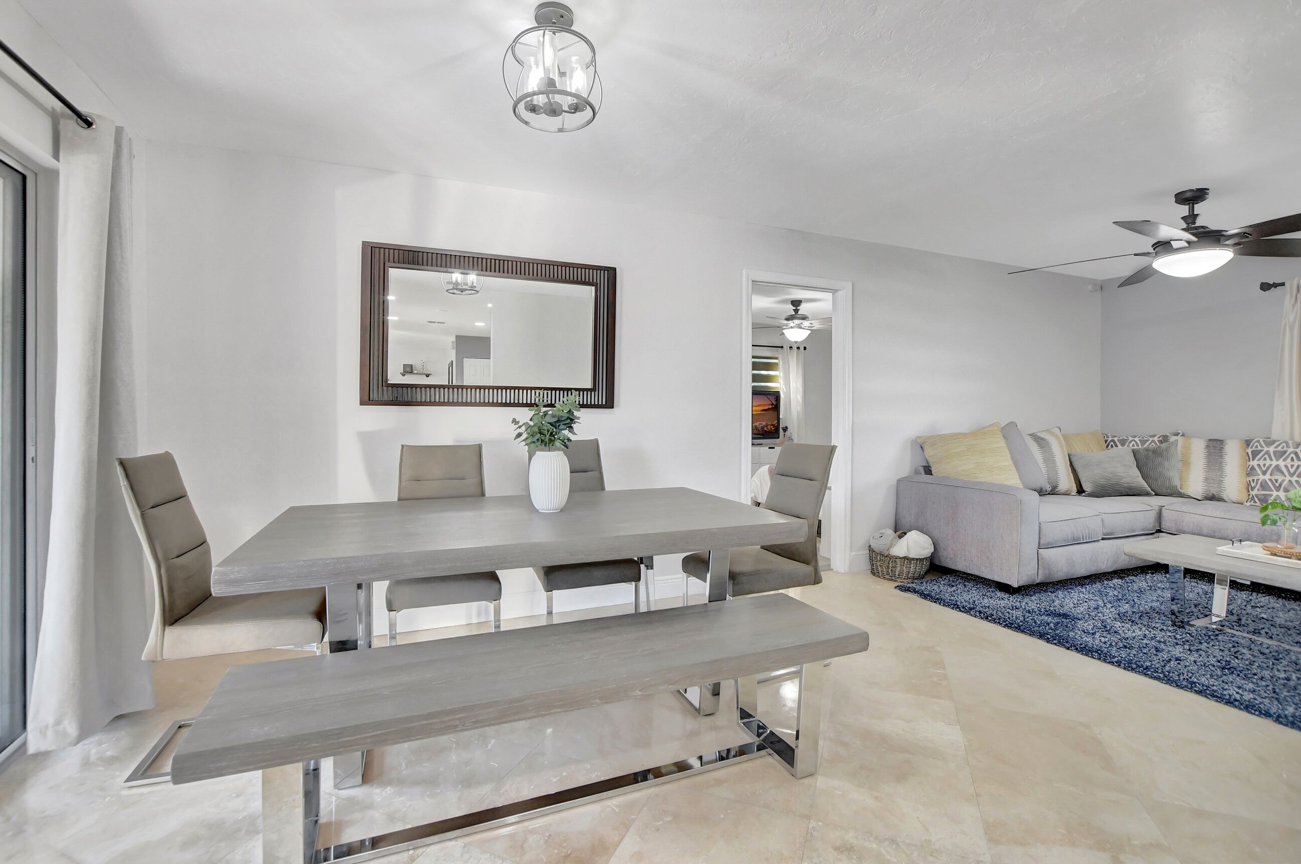 A modern living room with a dining table, sofa, and ceiling fan.