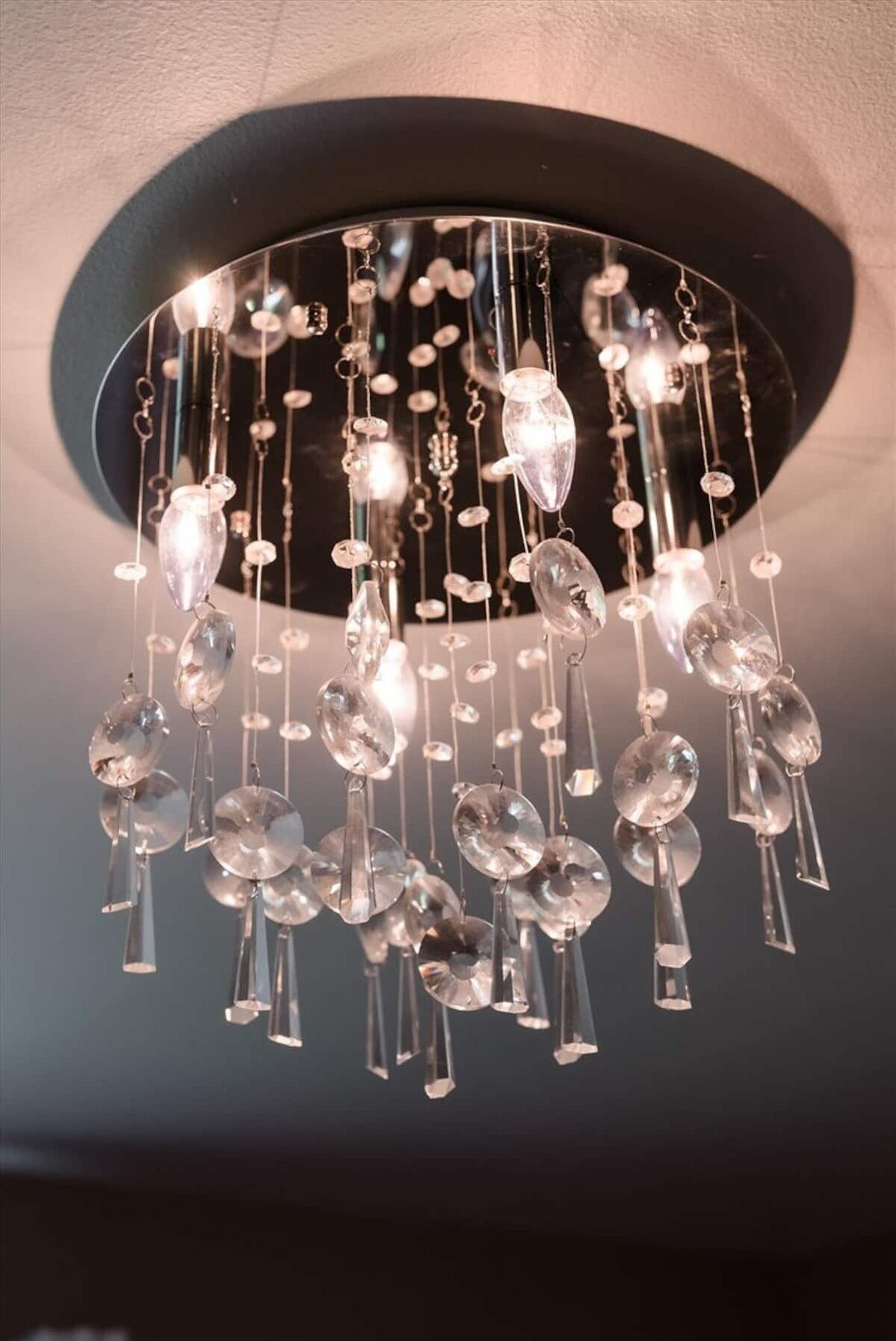 Un lustre orné de nombreux éléments en cristal transparent et de plusieurs ampoules.