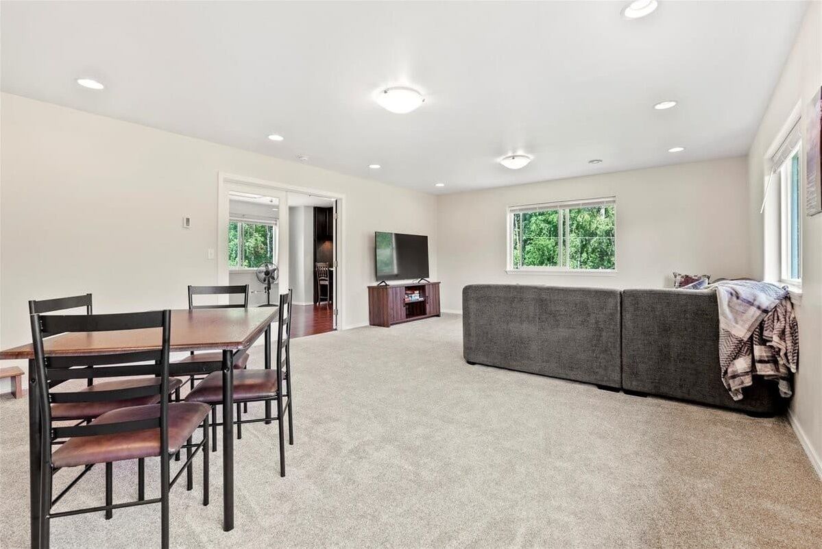 A spacious living area with a dining table, chairs, a sofa, and a TV.