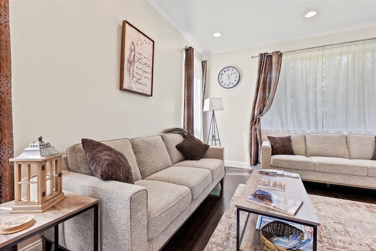 A living room with two sofas, a coffee table, a floor lamp, and a wall clock.