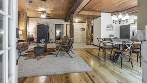 A rustic interior with a wooden ceiling, a dining area with a table and chairs, a leather sofa, and a fireplace. - The Log Palace Private Guest Suite 2 Bedroom Cabin by RedAwning (Cottontown)