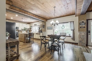Una cocina amplia con pisos de madera, un comedor con mesa y sillas de madera, y una pared de acento de piedra.