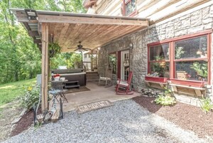 Un patio cubierto con pared de piedra, mobiliario exterior y un jacuzzi.