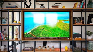 A flat-screen TV on a wooden TV stand surrounded by shelves with books, decorative items, and a vase. - Modern Villa Noel with swimming pool (Valica)