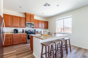 Una cocina moderna con armarios de madera, encimera de granito y una isla grande con taburetes de bar.