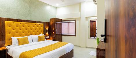 A hotel room with a large bed, wooden headboard, bedside tables, and a ceiling fan.