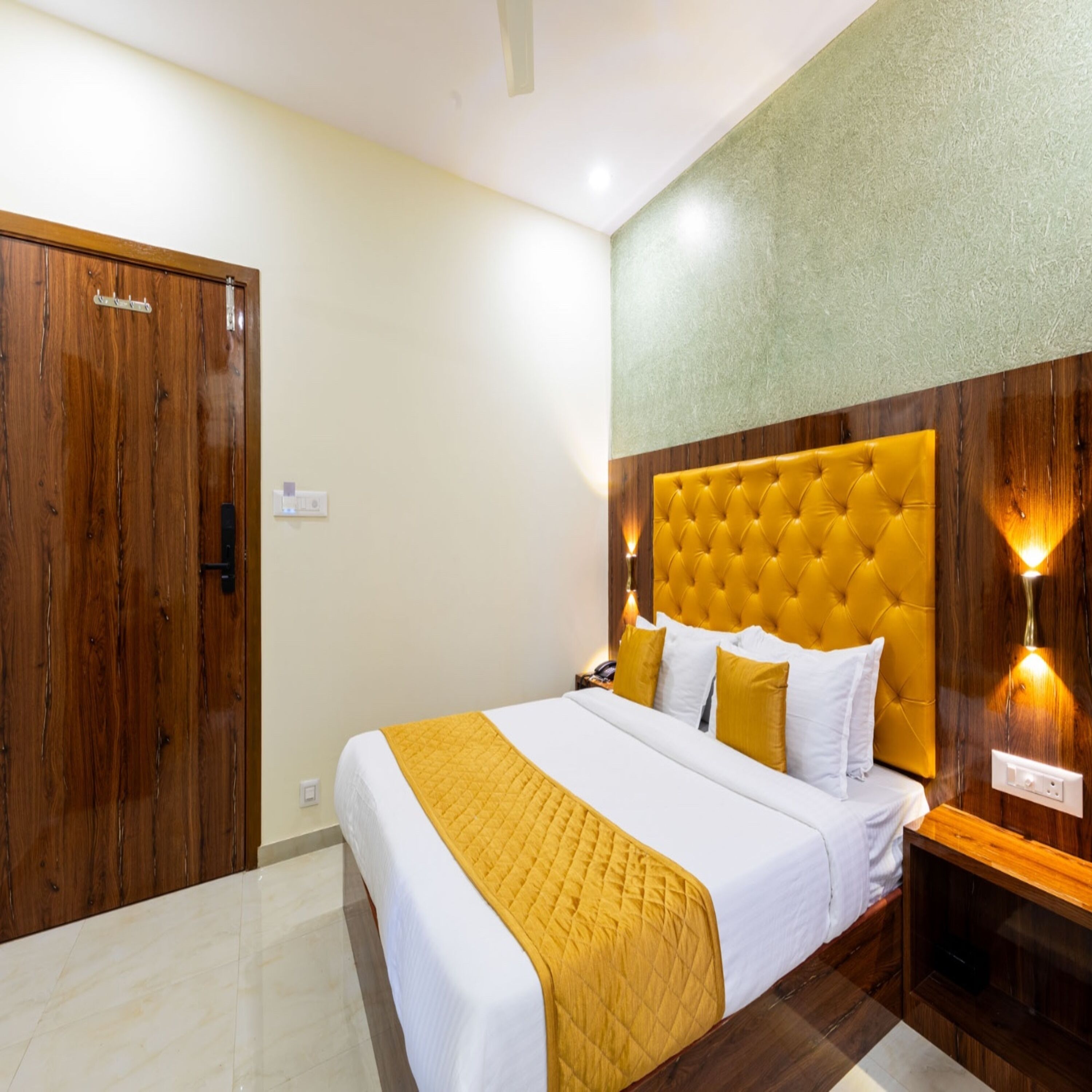 A hotel room with a large bed, wooden wardrobe, and a bright yellow headboard.