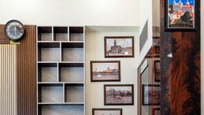 A hallway with a wooden panel wall, a clock, framed pictures, and a Lisbon poster. - Hotel Imperial (Mumbai)