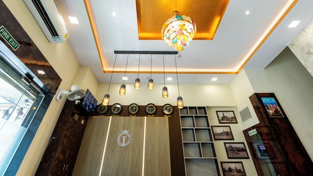 A hotel lobby with a modern chandelier, a clock, and a fire exit sign. - Hotel Imperial (Mumbai)