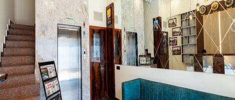 A lobby with a marble floor, a blue sofa, an elevator, and a staircase.