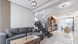 Ein modernes Wohnzimmer mit grauem Sofa, einem Holztisch und einer Treppe, die in einen oberen Bereich führt.