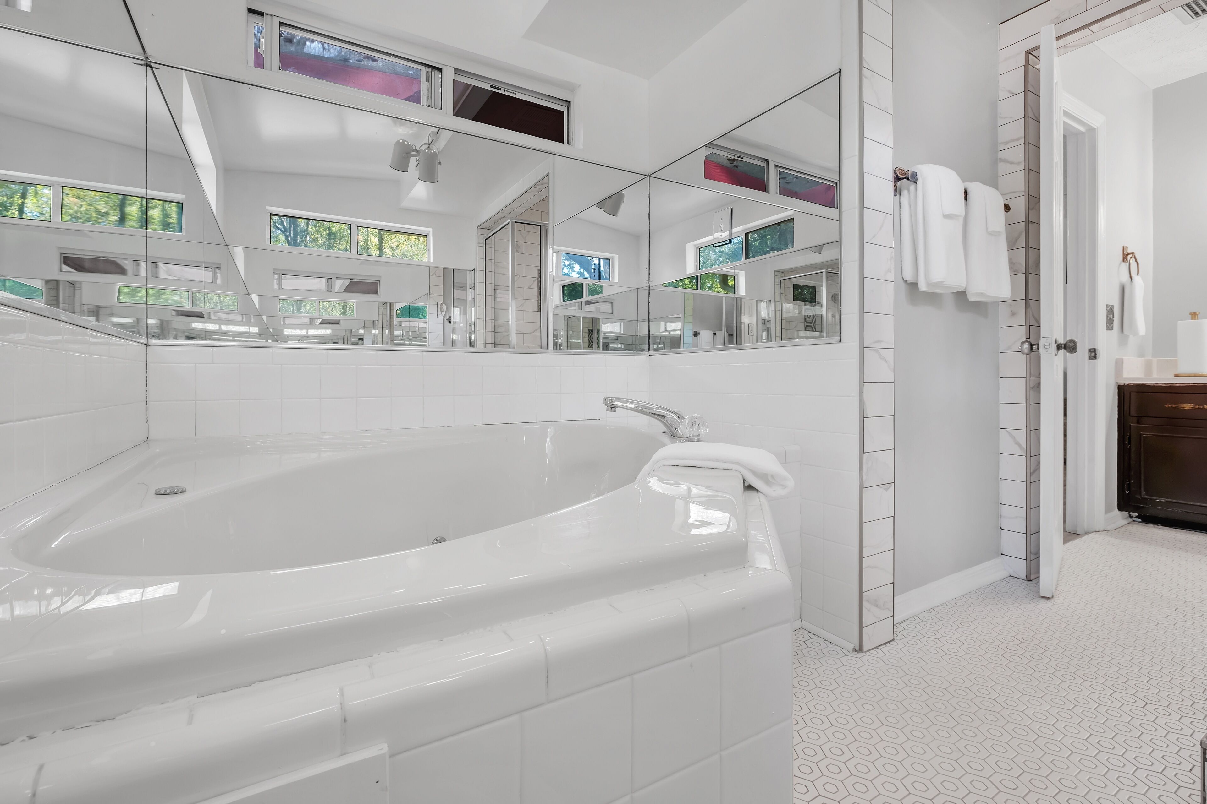 Une salle de bain moderne dotée d’une grande baignoire, d’une douche à l’italienne et d’un miroir qui reflète la pièce.