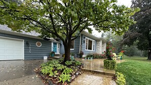 Ein Wohnhaus mit Garage, einem Vorgarten mit Baum und einem Weg zum Eingang.