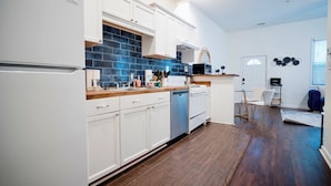 A modern kitchen with white cabinets, a blue backsplash, and a dishwasher.