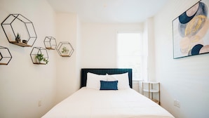A bedroom with a large bed, a dark headboard, and multiple hexagonal wall decorations.