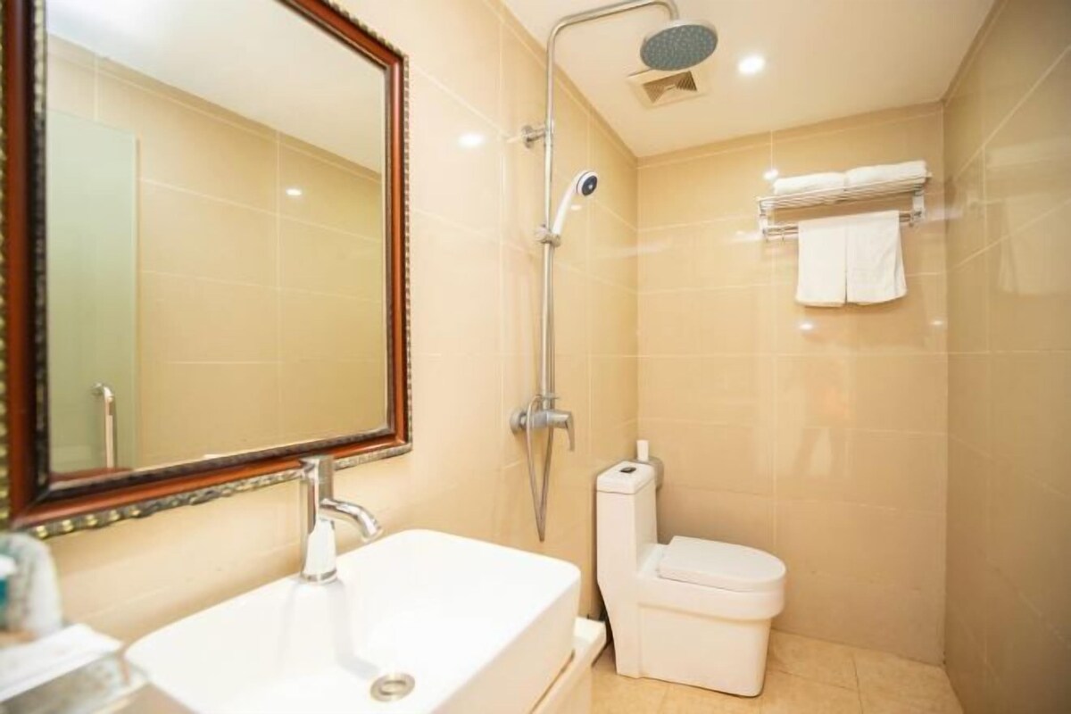 A modern bathroom with a large mirror, a sink, a toilet, and a shower.