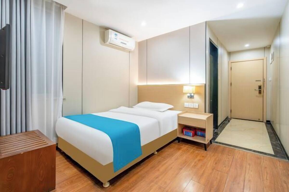 A hotel room with a bed, bedside table, and a nightstand.