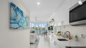 A modern kitchen with white cabinetry, a large black microwave, and a view to the outside. - EL SOL OCEAN VIEW / EXCLUSIVE  (San Juan)