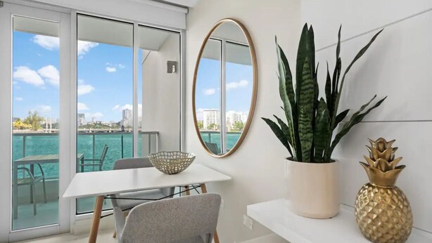 A balcony with a table, chairs, a bowl, a mirror, a plant, and a decorative pineapple. - EL SOL OCEAN VIEW / EXCLUSIVE  (San Juan)