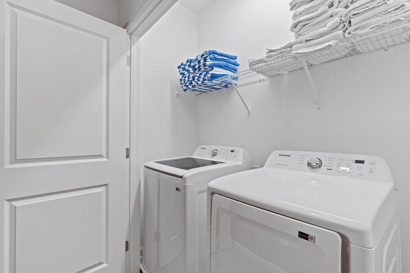A laundry room with two white washing machines, a blue and white towel rack, and a white door. - Luxury Meets Fun: 8BR Home with Themed Bedrooms (Orlando)