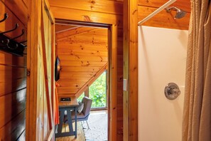 L’intérieur d’une cabane en bois comprend une douche, un banc et une table avec une chaise.