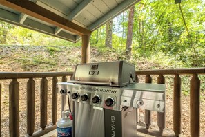 Un barbecue au gaz portatif doté d’un écran numérique et de plusieurs brûleurs, placé sur une terrasse en bois avec une rambarde.