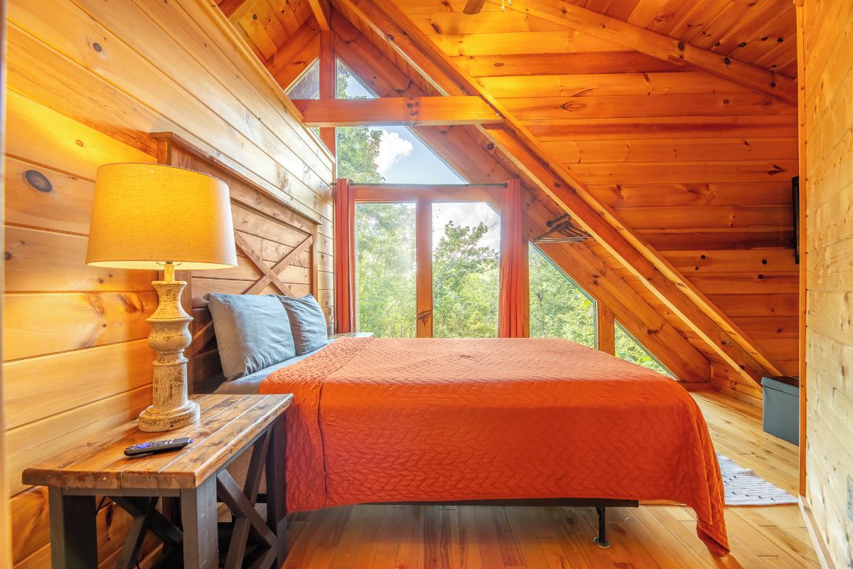Quarto de sótão aconchegante com cama, abajur e janela.