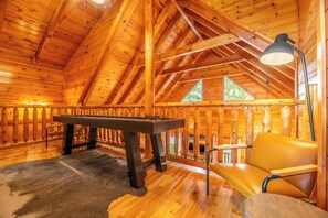 A wooden interior with a pool table, a chair, and a lamp.