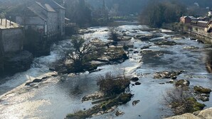 Un riu serpegen per una vila amb edificis de pedra i un pont.