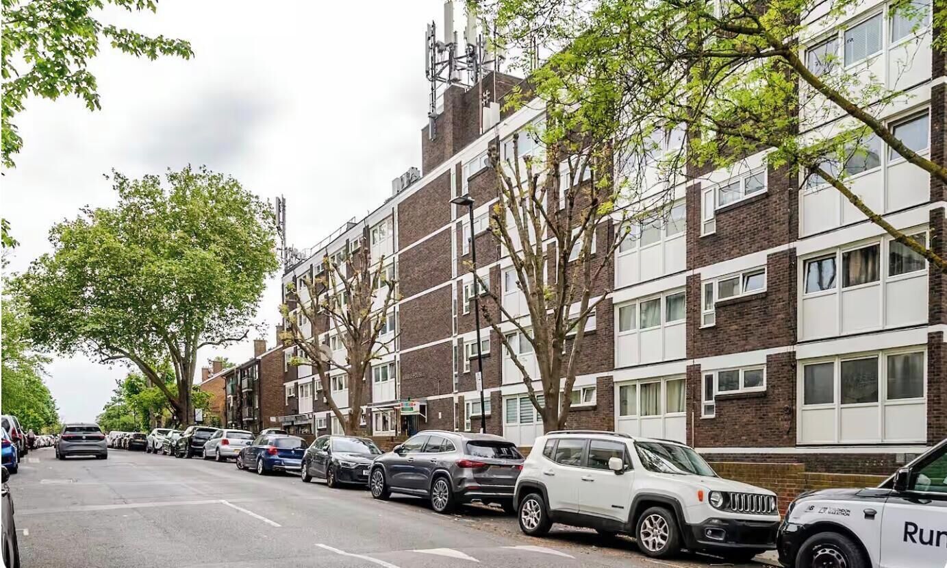 Eine Reihe geparkter Autos säumt eine Straße, die von mehrstöckigen Wohnhäusern gesäumt wird.