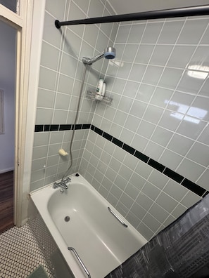 Un baño con bañera, ducha y barra para toallas.