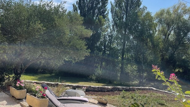 Um jardim com degraus de pedra que levam a um espaço de estar com cadeiras de lounge.