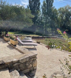 Un espace jardin agrémenté d’un escalier en pierre menant à un coin salon avec des fauteuils confortables.