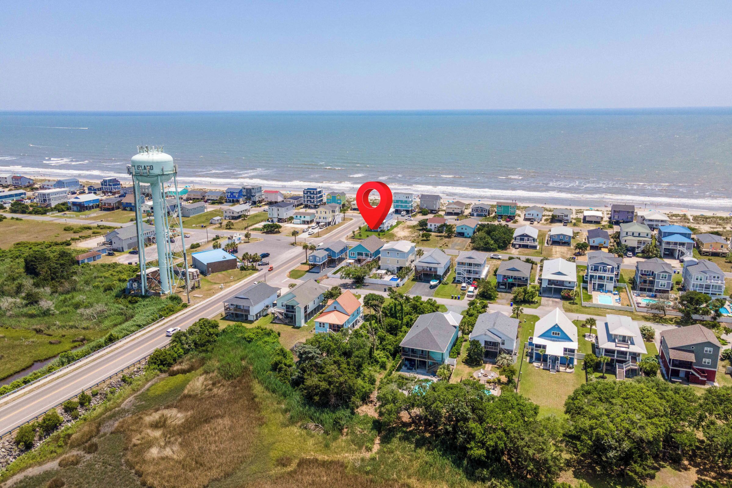 An aerial view of a coastal residential area with houses, a water tower, and a beach.