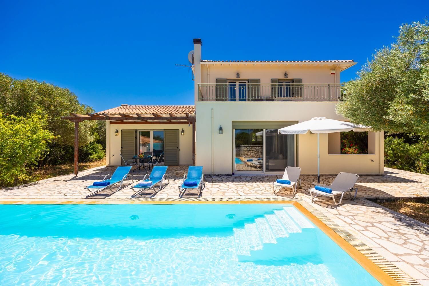 A two-story house with a swimming pool, outdoor seating, and a pergola.