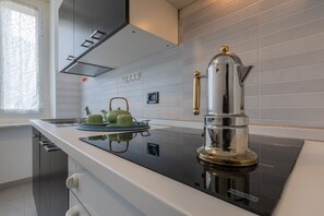 A modern kitchen with a stainless steel espresso machine, a green tea set, and a window with a geometric curtain. - Casa Gabel by Wonderful Italy (Torino)