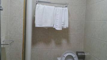 A bathroom with a toilet, a towel rack with towels, and a shower area.